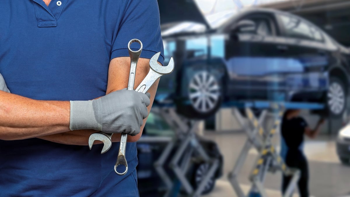 Mechanic with crossed arms holding wrenches